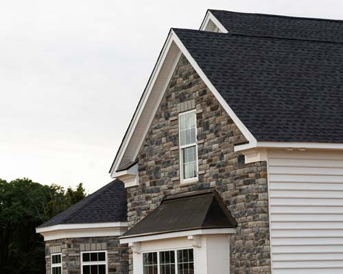 Multi-colored brick home with dark shingle roof